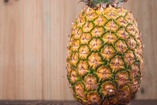 Fresh Pineapple being seen from a the top on a wooden background. Close up view of a pineapple