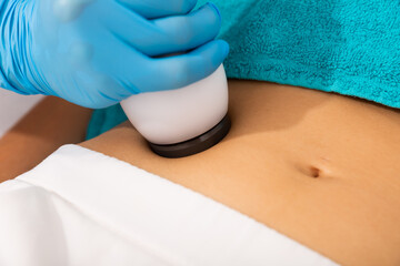 Closeup of female abdomen during ultrasonic fat cavitation procedure at aesthetic clinic