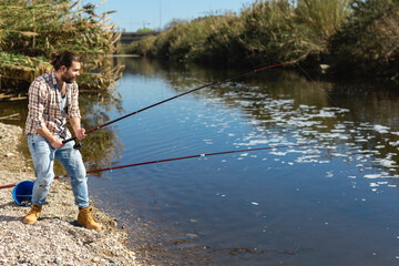 Fototapeta na wymiar Happy fisherman pulls fish out of the river. High quality photo