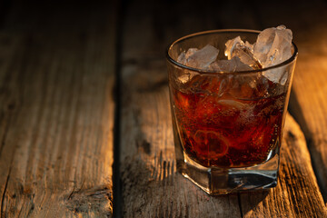 Glass of whiskey with ice on wooden background. Concept of delicious alcoholic drinks. Advertising and promotion. Bar card.
