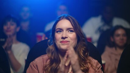 Amazed woman applauding at movie premiere. Smiling girl enjoying film in cinema.