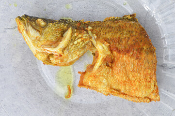 Top view of fried Barramundi fish on a glass plate isolated on a white background. Delicious food.