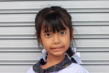 Cute Asian little girl wearing a school uniform looking at the camera and smile.