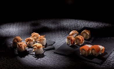 Appetizing rolls on a textured black background. Japanese food concept. Close-up. Copy space.