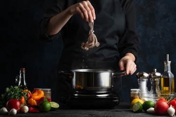 Professional chef cooking traditional asian dish and puts octopus into pot with boiling water. Backstage of preparing seafood on dark blue background. Concept of exotic asian cuisine. Frozen motion.