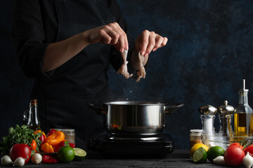Macro shot of chef cooking asian dish and puts octopuses into pan with boiling water. Backstage of preparing seafood on dark blue background. Concept of exotic asian cuisine. Frozen motion.
