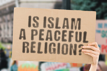 The question " Is a peaceful religion? " on a banner in men's hand with blurred background. Religion. Belief. Violence. Unlawful. Violation. Dangerous