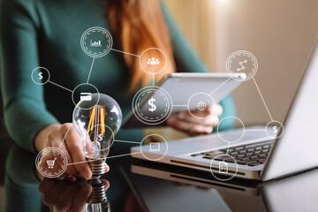 business man hand holding lightbulb with using smartphone and calculator to calculate and money...
