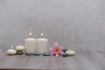 Fototapeten Spa setting with plumeria flowers, five candles and gray stones and on wood background   © Mee Ting