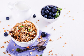 Muesli with blueberris in a bowl   on white wooden background. Delicious and healthy breakfast.
