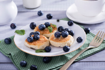 Cottage cheese pancakes, syrniki on white plate with  fresh blueberries. Healthy and delicious morning breakfast.Top view, copy space.