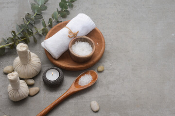 Fototapeta na wymiar rolled towel and green eucalyptus and salt in bowl ,herbal,ball,stones on a gray background with copy space