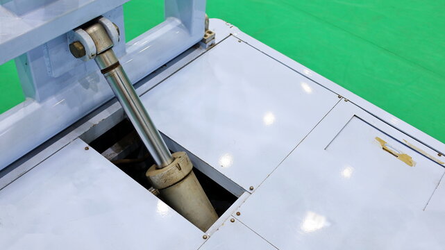 Gray hydraulic cylinders and pistons.Chrome-plated hydraulic cylinder mechanism for lifting and bracing basketball bases. On a green background with a copy area. Select the content and close the focus