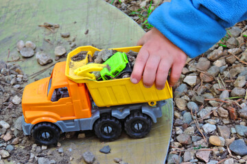 child playing with toy truck And excavator,  toys  on  pile of gravel for  village road