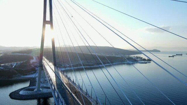 View from above. Russian bridge across the Eastern Bosphorus Strait in Vladivostok. The camera rises over the bridge blocked by the ice storm. Droga is blocked due to wearing. Sunset, evening.