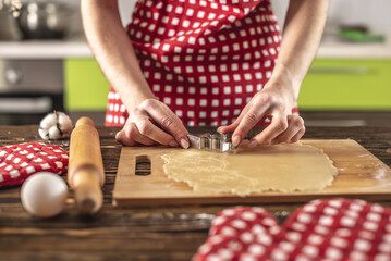 Woman making delicious homemade cookies in the shape of Christmas tree in her kitchen. Concept of fresh homemade cakes and cozy festive atmosphere