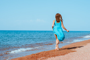 girl in a dress runs along the seashore