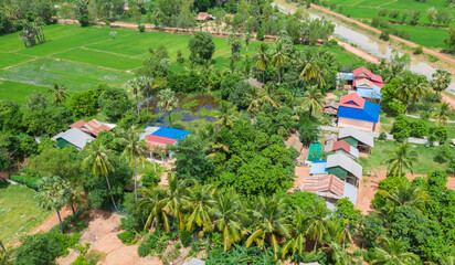 Obraz premium Main dirt road in rural village in Cambodia. There are houses on either side of the road.