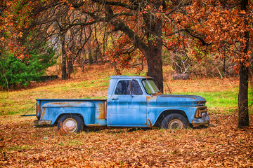 Old, abandoned blue truck surrounded by beautiful fall foliage in autumn - Powered by Adobe