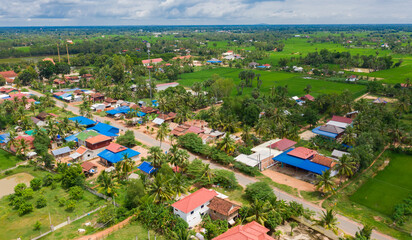 Obraz premium Main dirt road in rural village in Cambodia. There are houses on either side of the road.