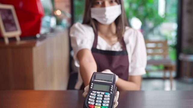 Asian Waitress with face mask hold credit card reader for contactless payment, 4K Slow motion Dolly Close up.
