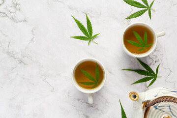 two cups of hemp tea with hemp leaves put on white marble floor