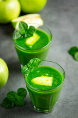 two glasses of green apple healthy smoothie put next to fresh green apples