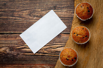 chocolate muffins and empty white paper put on wooden floor