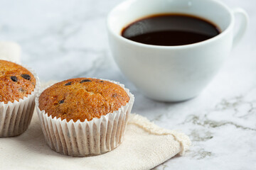 chocolate muffins and a cup of coffee on white marble floor