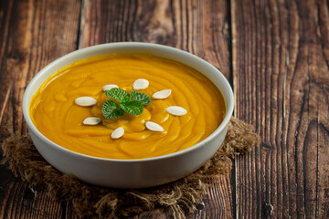 pumpkin soup in white bowl placed on wooden floor.