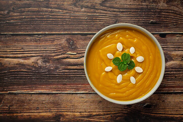 pumpkin soup in white bowl placed on wooden floor.