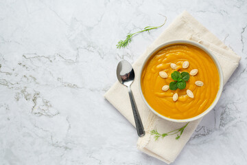 a bowl of pumpkin soup place on white fabric