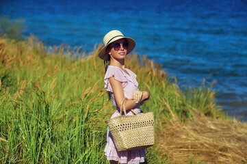 Beautiful girl in a summer dress and a fashionable hat in nature