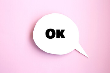 White paper speech bubble concept with inscription ok. Cartoon speech with clipping path on bright background with contrasting shadow