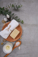 Rolled towels and soap in bowl ,salt in wooden spoon, candles ,stone and on grey background
