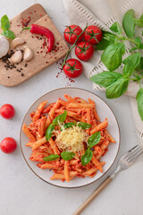 Plate of penne pasta with tomato sauce on light background