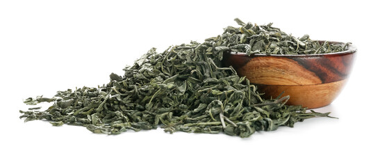 Bowl with dry green tea on white background