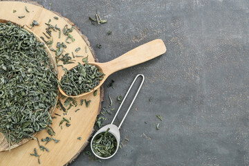 Spoons with dry green tea on dark table