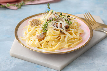 Plate of tasty pasta with chicken and mushrooms on color table
