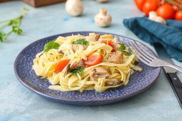 Plate of tasty pasta with chicken and cherry tomatoes on color table