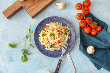 Plate of tasty pasta with chicken and cherry tomatoes on color table