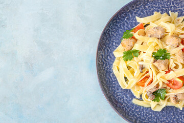 Plate of tasty pasta with chicken and cherry tomatoes on color table