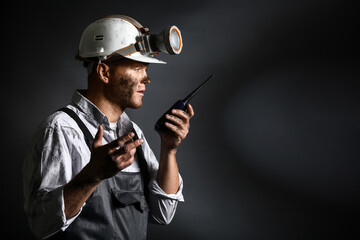 Fototapeta na wymiar Miner man with two-way radio on dark background