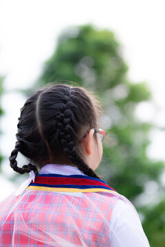 Vertical Photos. Braided Girl Stood Back And Looked To The Front. Children Wearing Graduation Gowns In Kindergarten. Girls 5-6 Years Old.