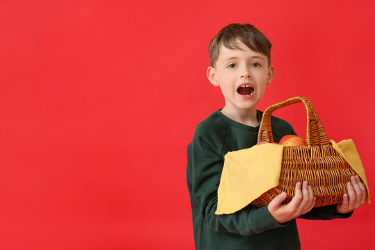 Cute Little Boy Holding Basket With Apples On Color Background