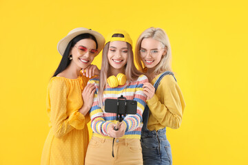 Obraz premium Beautiful young women taking selfie on color background