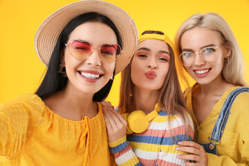 Beautiful young women taking selfie on color background
