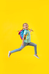 Fototapeta na wymiar Jumping little schoolgirl on color background