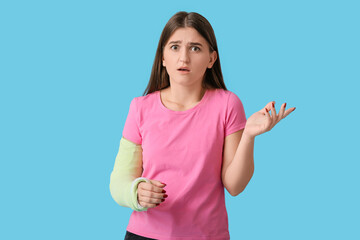 Young woman with broken arm on color background