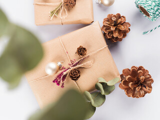 Christmas festive scene with wrapped zero waste presents, golden decor, pine cones and eucaliptus on gray background.